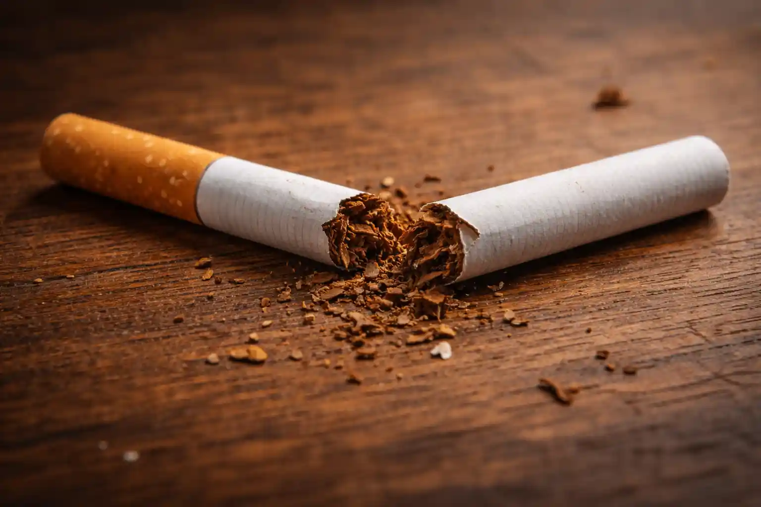 Broken cigarette snapped in half on a wooden surface